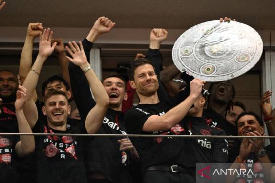 Foto: Pelatih Bayer Leverkusen Xabi Alonso (kanan) menggenggam replika trofi juara setelah timnya dipastikan menjuarai Liga Jerman.