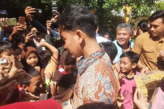 Foto: Gibran Rakabuming Raka membagikan buku tulis bersampul foto anaknya, Jan Ethes ke anak-anak SDN di Surabaya.
