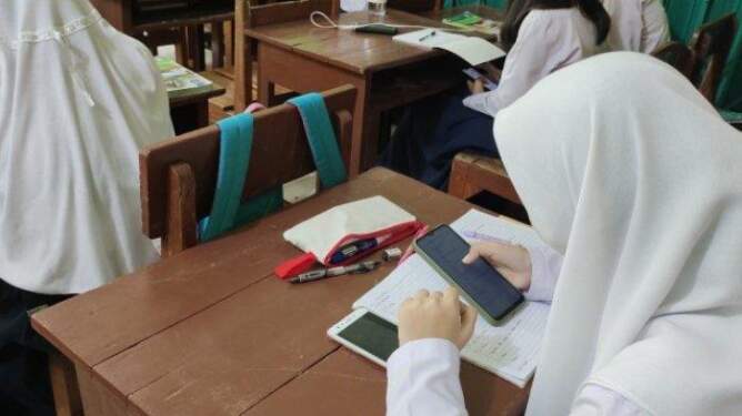 Foto: Ilustrasi penggunaan HP di kelas.