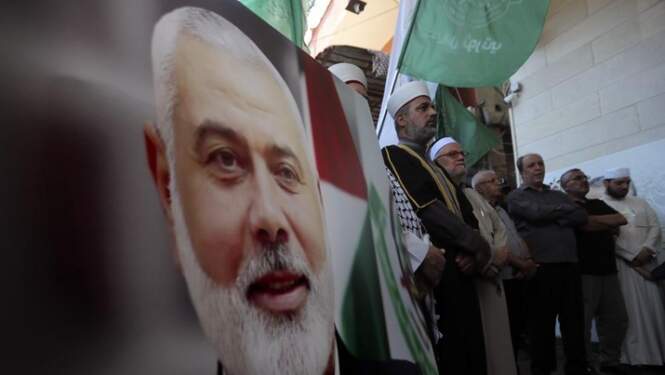 Foto: Anggota Hamas berdiri di samping poster kepala politik Hamas Ismail Haniyeh selama protes untuk mengutuk pembunuhannya, di kamp pengungsi Palestina al-Bass, di kota pelabuhan selatan Tyre, Lebanon, Rabu, 31 Juli 2024. (AP Photo/Mohammed Zaatari)