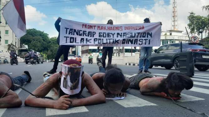 Foto: Massa berdemonstrasi di depan Kantor Wali Kota Medan dengan membawa poster Bobby Nasution bersalaman dengan AGK.