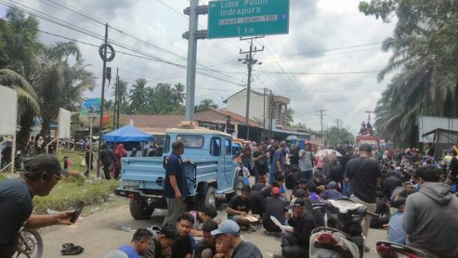 Foto: Warga Asahan makan bareng sambil memblokir akses jalan Tol Kisaran.