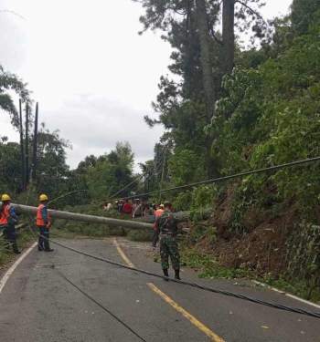 Foto: Petugas BPBD, TNI-Polri dan warga saat mengevakuasi pohon tumbang di ruas jalan Siantar-Parapat.