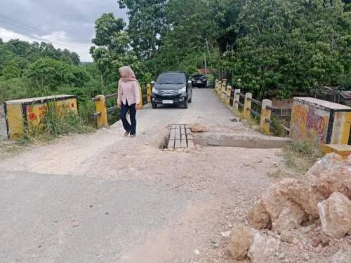 Foto: Seorang wanita yang mengendarai mobil tidak berani melintasi jembatan yang rusak di Kecamatan Batang Onang.