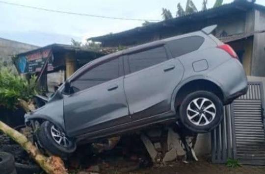 Foto: Sebuah mobil minibus abu-abu terlihat dalam posisi "terbang" dan tersangkut di atas teras rumah warga di Desa Perdamaian, Dusun 3, Kecamatan Binjai, Kabupaten Langkat.(Istimewa)